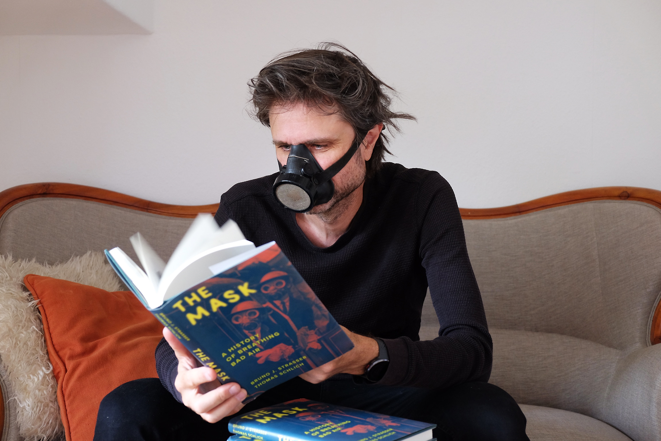 Bruno Strasser reading his book The Mask whilst wearing a mask.