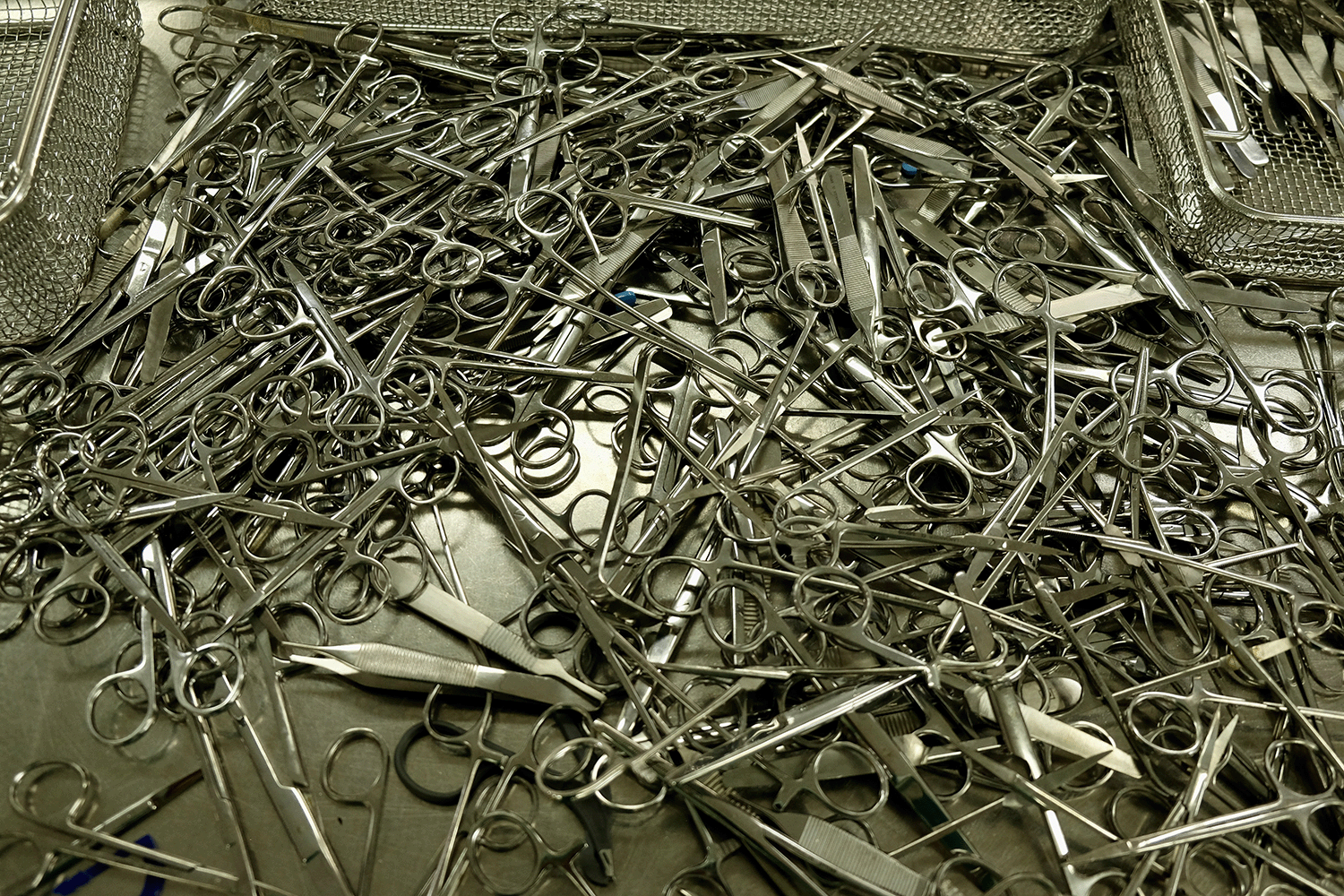 Large pile of scissors on chrome table.