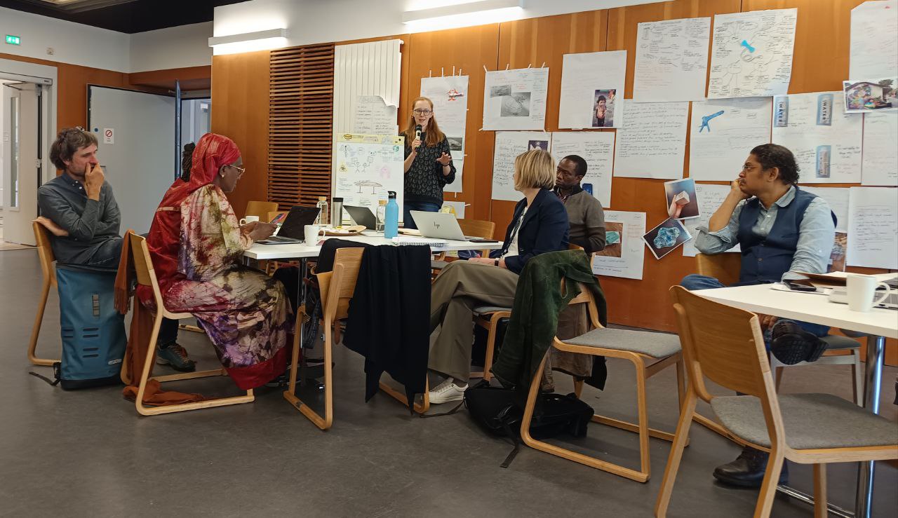 A group of academics sit around a table discussing pathways and barriers to collaboration.