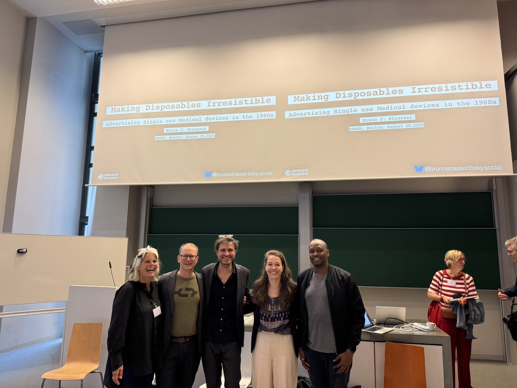 Five researchers from After the Single Use stand in front of a projector screen in a conference room. 