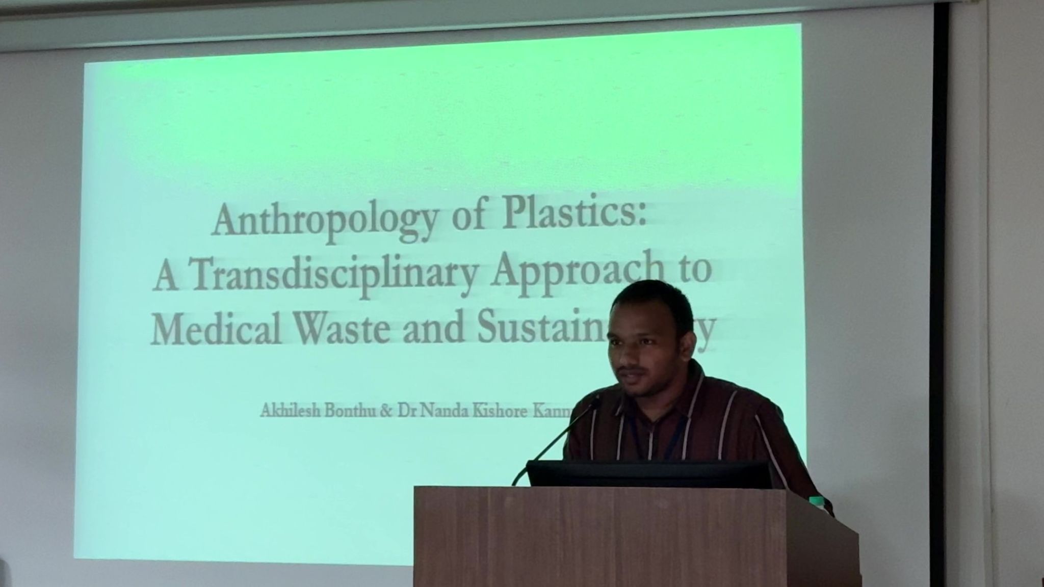 Akhilesh Bonthu stands at the front of the lecture hall, with the title of his presentation on the screen