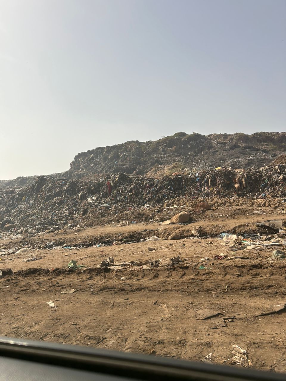View from car window of large dumpsite. 