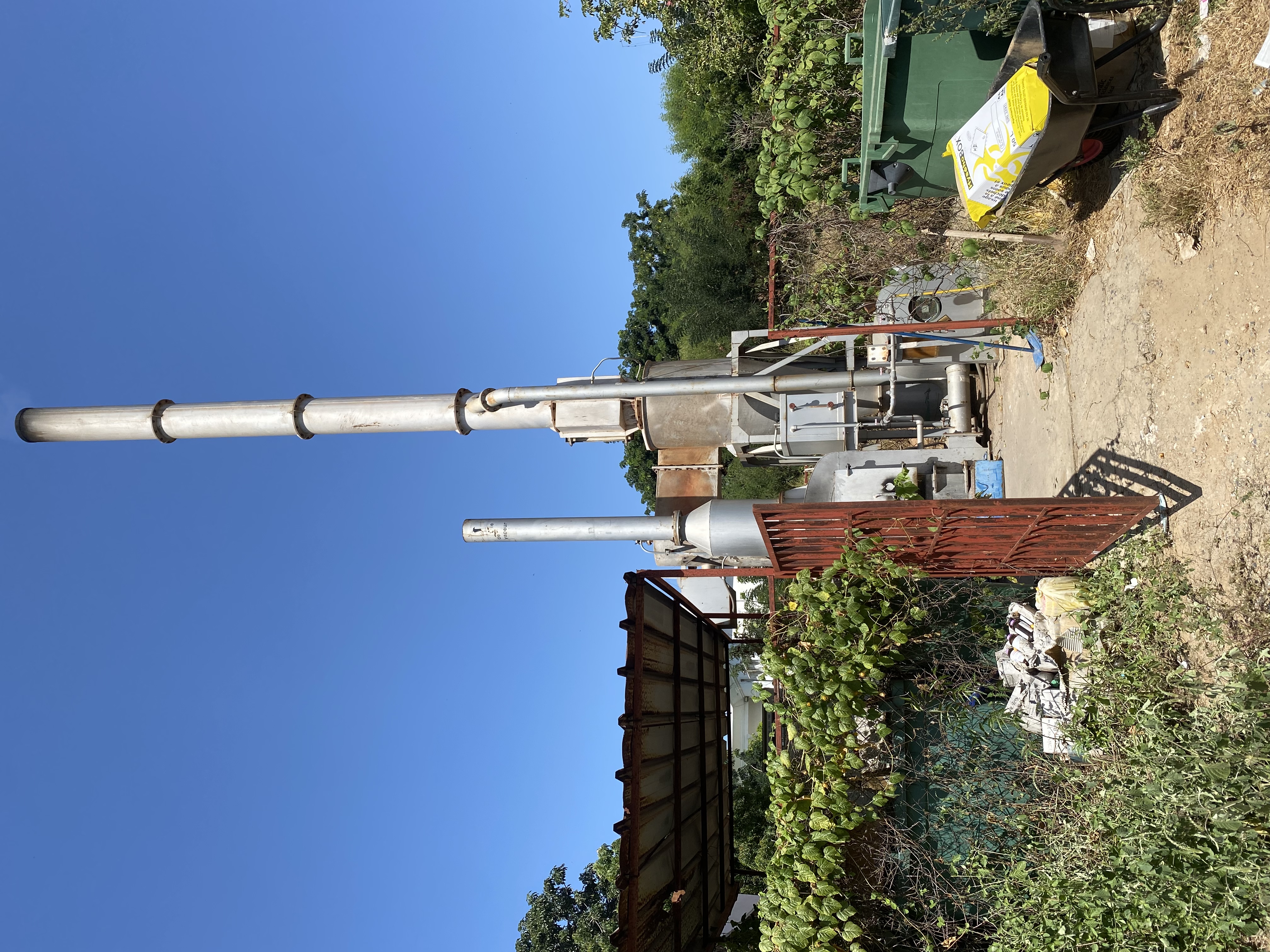Petrol fuelled incinerator with a large chrome chimney set against a blue sky. 