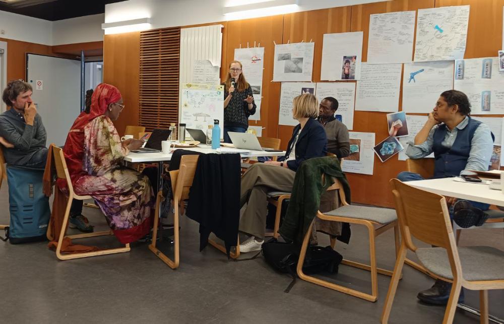 A group of academics sit around a table discussing pathways and barriers to collaboration.