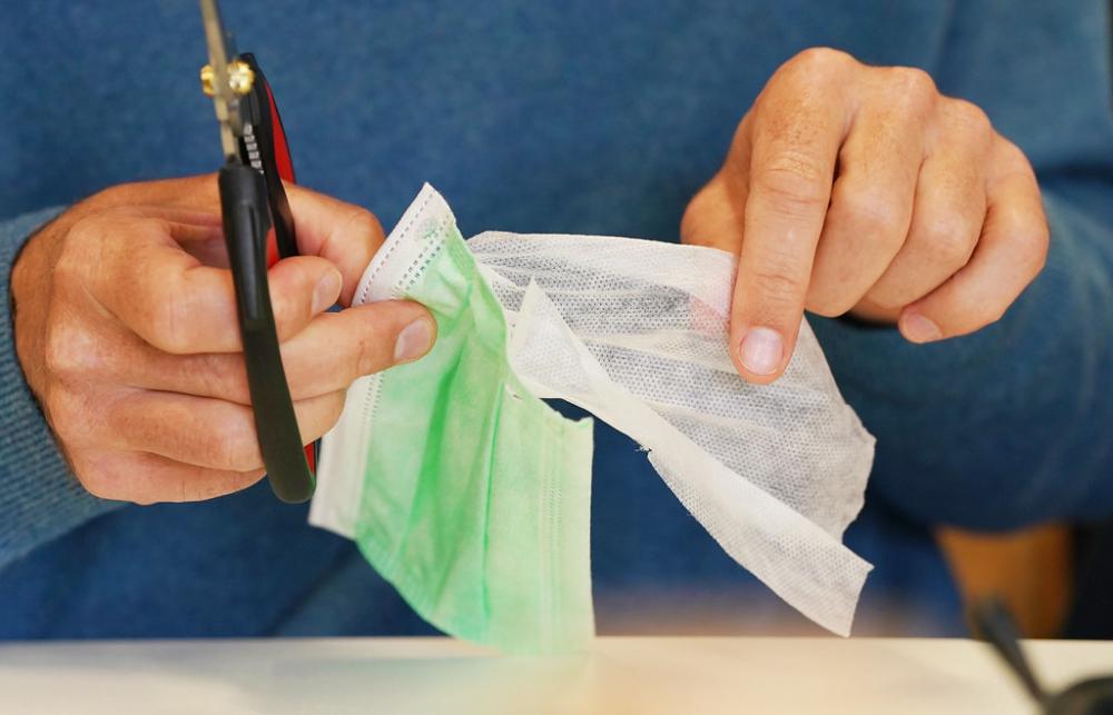 A researcher teases apart the different layers of a single-use mask