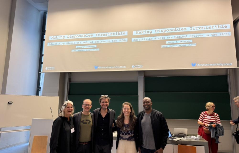 Five researchers from After the Single Use stand in front of a projector screen in a conference room. 