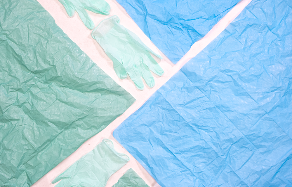 Green and blue plastic materials from medical devices and PPE and laid out on a white table. 