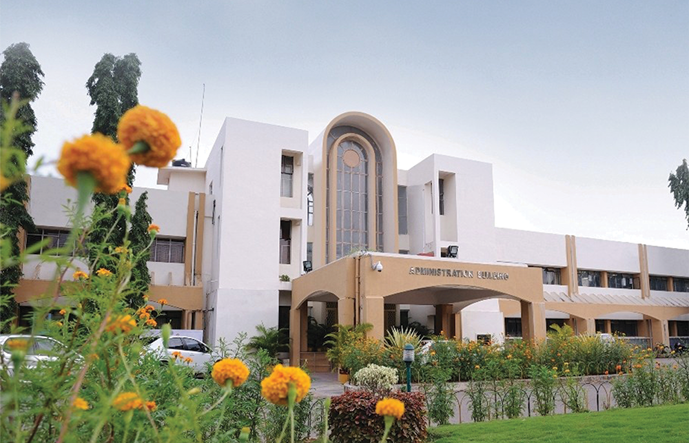 University of Hyderabad building with blooming flowers in foreground and bright skies. 